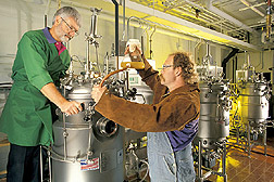 Microbiologist and technician add microorganisms to bioreactors: Click here for full photo caption.