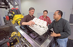 Chemist and two Regale Corporation collaborators remove the bottom part of a wine bottle carton from its mold: Click here for full photo caption.
