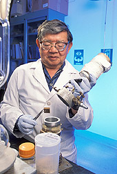 Chemist removes a sample of wood from chamber: Click here for full photo caption.