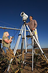 Agricultural engineer (on ladder) and hydrologic technician determine the water loss from a field by measuring the sensible heat flux with a large-aperture scintillometer: Click here for full photo caption.