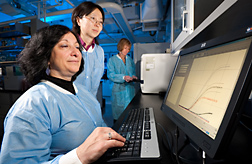 In efforts to develop new techniques to quickly and reliably identify pathogenic E. coli serogroups, microbiologist (left) and molecular biologist (center) view real-time PCR results from study samples as another microbiologist loads a thermal cycler with more samples for testing: Click here for full photo caption.