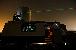 A laser beam is positioned to track the particulate plume from a swine facility: Click here for full photo caption.