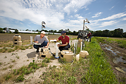 ARS soil scientist (left) and UMES associate professor collect samples of groundwater before and after it is filtered through an underground “curtain” of gypsum: Click here for full photo caption.