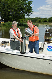 ARS agronomist (left) and soil scientist collect a water sample on the Choptank River for pesticide and nutrient analyses: Click here for full photo caption.