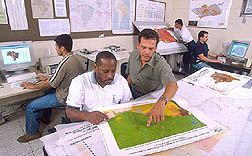 Geographic information specialist and research assistant reviewing data maps and charts: Click here for full photo caption.