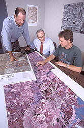 Hydrologist, hydraulic engineer, and technician analyze high-altitude aerial photographs: Click here for full photo caption.