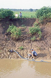 Hydrologist uses a bore hole shear device while technician prepares for a submerged-jet test: Click here for full photo caption.