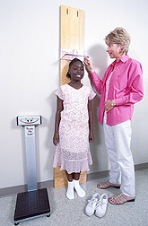 Clinical coordinator measures height and weight of a study participant: Click here for full photo caption.