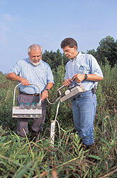 Ecologist and agricultural engineer pump water from a sampling well: Click here for full photo caption.