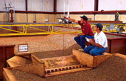 Engineers measure bed profiles in riprap upstream in a sealed-down model of the structure. Click here for full photo caption.