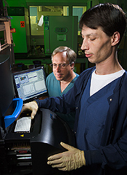 Microbiologist and technician load samples into a fluorescent real-time thermocycler: Click here for full photo caption.