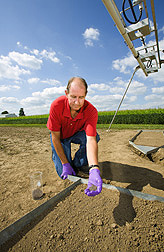 Soil scientist applies pelletized gypsum and polyacrylamide (PAM) to a soil surface to control erosion prior to a rainfall-simulation test: Click here for full photo caption.