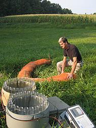 Soil scientist checks the placement of a compost-filled filter sock in a grassed waterway: Click here for full photo caption.