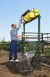 Entomologist David Taylor adjusts the settings on a sprayer used to automatically treat cattle with a stable fly repellent: Click here for photo caption.