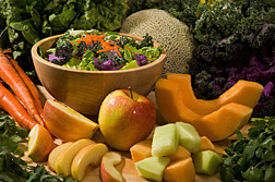 Carrots, apples, melons and salad greens surrounding a bowl of salad.  Link to photo information