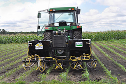 Tractor-mounted system for spraying corn grit to shred the leaves of weeds growing between crop rows.