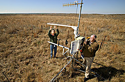 Plant physiologist and rangeland scientist adjust a weather station: Click here for full photo caption.