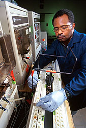 Chemist James Hill places water in an autosampler of the flow-through colorimetric autoanalyzer. Click here for full photo caption.