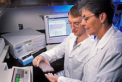 Chemist and physiologist examine a tray of serum samples: Click here for full photo caption.