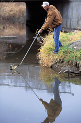 Technician collects a sample from a watershed in Ames, Iowa, during studies to refine the model: Click here for full photo caption.