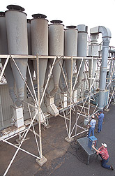A technician and two agricultural engineers conduct stack sampling on a cotton gin exhaust: Click here for full photo caption.