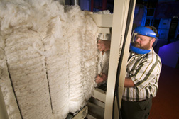 A machinist replaces a broken bale tie on a cotton bale: Click here for full photo caption.