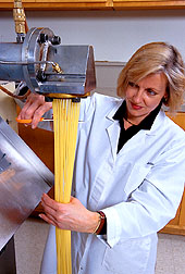 A physical science technician extrudes spaghetti which will be dried and test-cooked. Click here for full photo caption. 