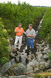ARS soil physicist (left) and landowner examine water quality in a ditch under controlled drainage management within the Choptank Watershed: Click here for full photo caption.