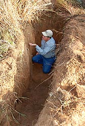 Soil scientist examines a soil profile beneath a native grassland site near Woodward, Oklahoma, before collecting samples for soil carbon analysis: Click here for full photo caption.