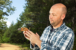 Chemist Charles Cantrell examines a burning dried male inflorescence from the breadfruit tree (Artocarpus altilis): Click here for full photo caption.