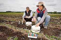 Using closed-vented chambers, biological science aide Rochelle Jansen (right) and soil scientist Jane Johnson collect gas emissions from soil at a research farm: Click here for full photo caption.