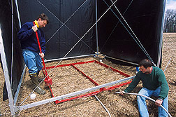 Hydrologic technician and soil scientist collect runoff inside a rainfall-simulator frame: Click here for full photo caption.