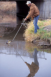 Technician collects a water sample: Click here for full photo caption.