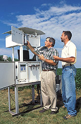 Laboratory director and technician examine a particulate sampler: Click here for full photo caption.