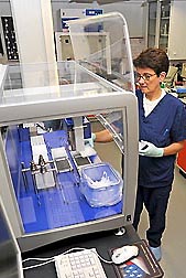 Microbiologist Teresa de los Santos uses an automatic liquid handling system to prepare multi-well plates to study immune responses of swine to foot-and-mouth disease virus infection using real-time PCR: Click here for photo caption.