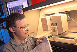 Chemist observes an automated DNA sequence instrument: Click here for full photo caption.
