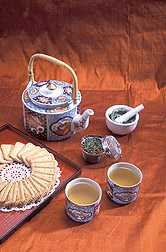 Tea kettle, tea leaves, two cups of tea, and cookies: Click here for full photo caption.