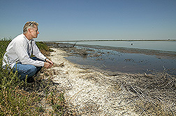 Soil scientist on salt-encrusted edge of an evaporation pond: Click here for full photo caption.