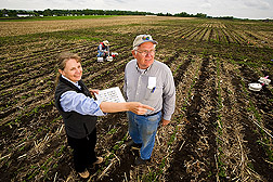 ARS soil scientists look for signs of erosion on plots used to test rates of biomass removal. In the background, a technician collects trace gas samples to test for carbon dioxide, nitrous oxide, and methane: Click here for full photo caption.