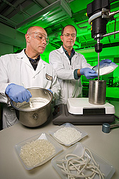 Food technologist (left) and plant physiologist prepare batches of starch-based dough which will be further processed by extrusion to form heat-expandable pellets: Click here for full photo caption.