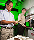 ARS scientist adds sugar beet pulp and polylactic acid to an extruder while ARS chemist examines bioplastic samples.