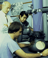 Scientists gathered around an electron microscope in the late 1980's. 