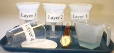 image of experiment setup with cups, funnels, filters, watch, and measuring cup