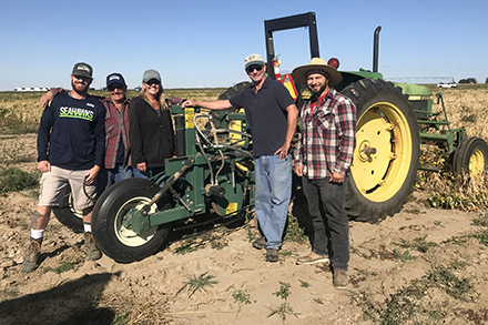 Five members of the harvest crew standing in front of a harvestor.