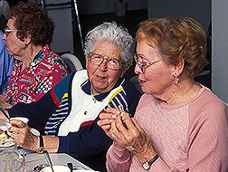 Three elderly women eating a meal.