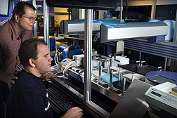 Photo: Researchers working at laboratory machine. Link to photo information