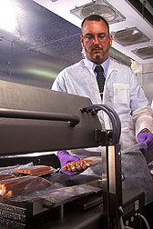 Photo: ARS researcher Christopher Sommers examines packets of hot dogs in a laboratory. Link to photo information