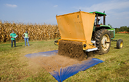 Technicians observe application of poultry litter on tarp placed behind the applicator. Link to photo information