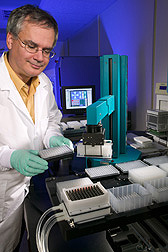Photo: Researcher using a robotic machine that automates preparation of DNA-sequencing reactions. Link to photo information
