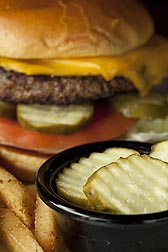 Photo: A cheeseburger on a bun with container of pickle slices. Link to photo information